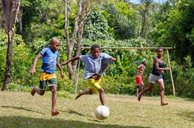 Maroantsetra, Madagaskar - 23 Kasım 2016: Mutlu Madagaskarlı çocuk, erkek ve kız çıplak ayak ile Madagaskar'daki Masoala yağmur ormanı yakınlarında onun köy arkasında futbol oynamak.
