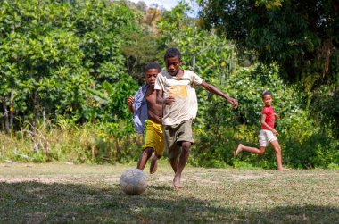 Maroantsetra, Madagaskar - 23 Kasım 2016: Mutlu Madagaskarlı çocuk, erkek ve kız çıplak ayak ile Madagaskar'daki Masoala yağmur ormanı yakınlarında onun köy arkasında futbol oynamak.