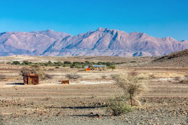Erongo Bölgesi çölündeki paslı teneke yığınından geleneksel Afrika kulübesi. Arka planda Brandberg Dağı var. Namibya vahşi doğası, yaşayan insanlar var.