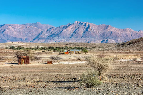 Erongo地域の砂漠の錆びた錫のシートから伝統的なアフリカの小屋 背景にはブランデンブルク山があります ナミビアの荒野に住む人々は — ストック写真
