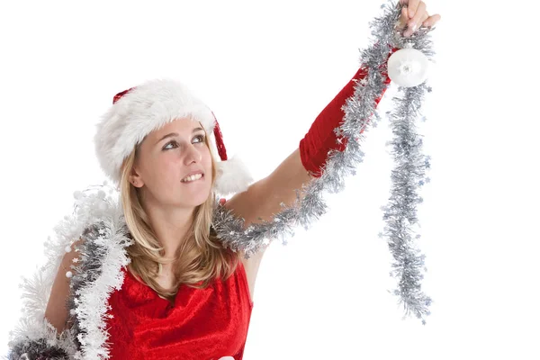 可爱的年轻女孩在圣诞老人的衣服试图达到挂在树上的小玩意 — 图库照片