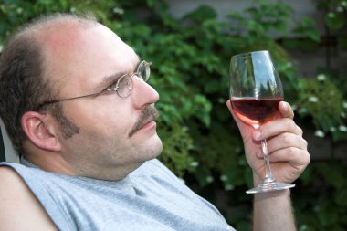 Bir bardak şarap zevk ve hayatını overthinking bahçede oturan adam