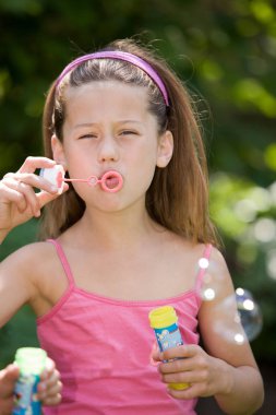 Güzel genç kız sabun köpüğü üflüyor. 
