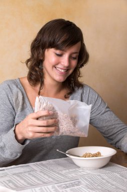 Güzel gülümseyen esmer yoğurt ve granola ile sağlıklı bir kahvaltı yapıyor.