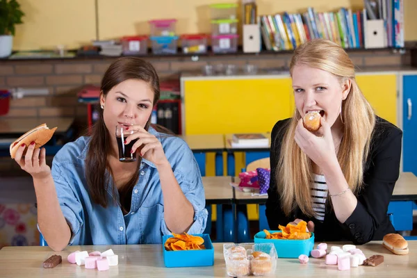 Két Iskoláslány Egészségtelen Ebédet Eszik Asztalnál — Stock Fotó