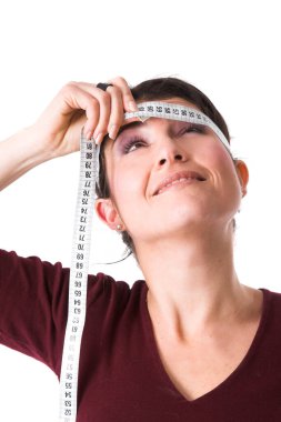 Güzel esmer, kafasının etrafında mezura tutuyor. 