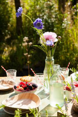 Meyve, salata, yoğurt ve çiçeklerle dolu yaz piknik masası. 
