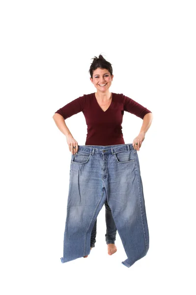 ブルネット女性保持アップ彼女の古い大きなジーンズ 体重減少 — ストック写真