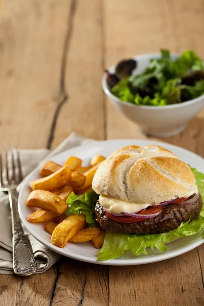 カフェでお皿の上にフライドポテトとおいしい新鮮なハンバーガー — ストック写真
