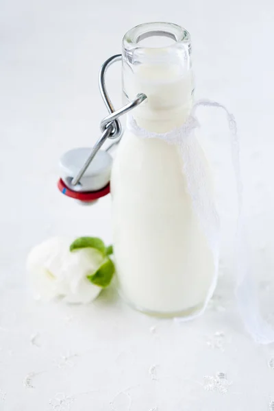 Petite Bouteille Lait Avec Une Fleur Blanche Sur Blanc — Photo