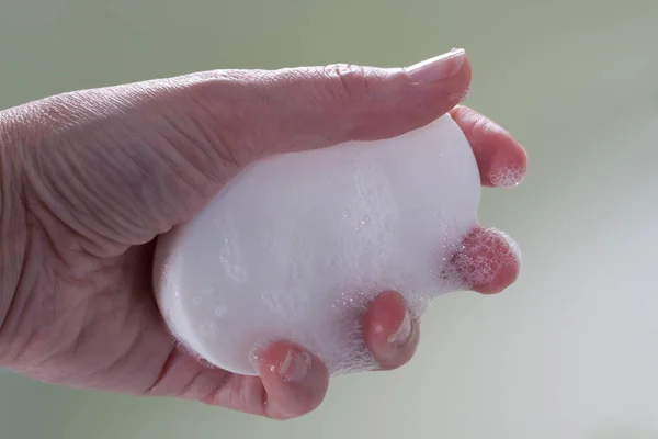 Mano sosteniendo una barra de jabón espumosa húmeda —  Fotos de Stock