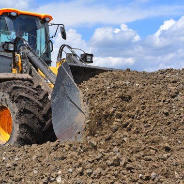 o kova yükleyici kirli bir yolun bir bölümünü onarıyor