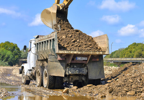 Kalush, Ukraine - August 18, 2018: Loading gravel in the car body on the construction of a protective dam near the town of Kalush.