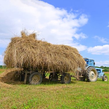 tractor carrying hay bale on field 