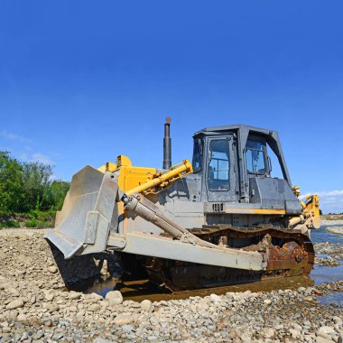 Buldozer, dağdaki küçük nehrin gelgitinde çalışır.
