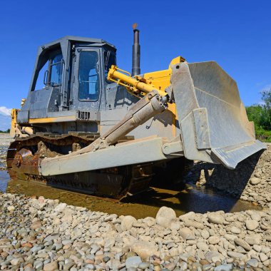 Buldozer, dağdaki küçük nehrin gelgitinde çalışır.