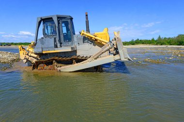 Buldozer, dağdaki küçük nehrin gelgitinde çalışır.