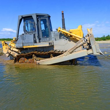 Buldozer, dağdaki küçük nehrin gelgitinde çalışır.