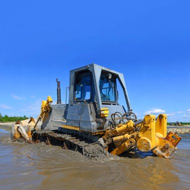 Buldozer, dağdaki küçük nehrin gelgitinde çalışır.
