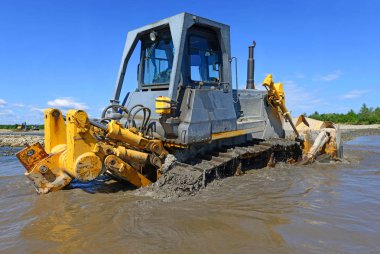 Buldozer, dağdaki küçük nehrin gelgitinde çalışır.