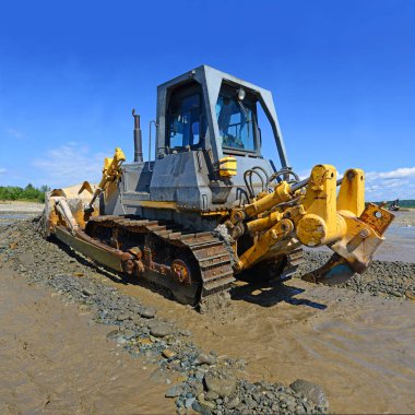 Buldozer, dağdaki küçük nehrin gelgitinde çalışır.