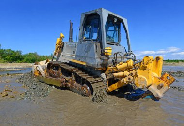 Buldozer, dağdaki küçük nehrin gelgitinde çalışır.