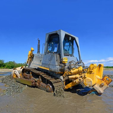 Buldozer, dağdaki küçük nehrin gelgitinde çalışır.