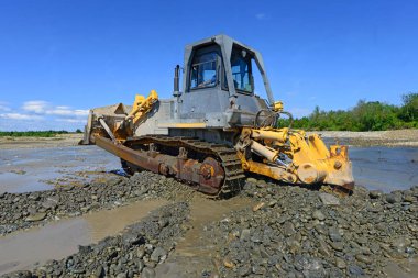 Buldozer, dağdaki küçük nehrin gelgitinde çalışır.