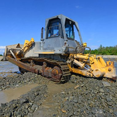 Buldozer, dağdaki küçük nehrin gelgitinde çalışır.