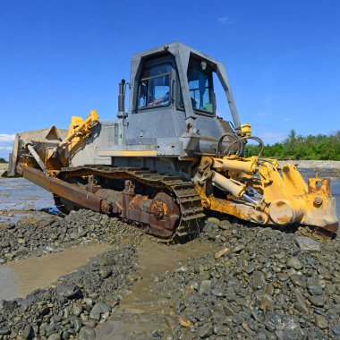 Buldozer, dağdaki küçük nehrin gelgitinde çalışır.