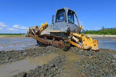 Buldozer, dağdaki küçük nehrin gelgitinde çalışır.