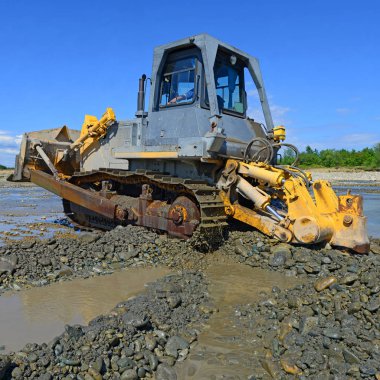 Buldozer, dağdaki küçük nehrin gelgitinde çalışır.