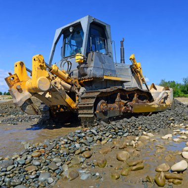 Buldozer, dağdaki küçük nehrin gelgitinde çalışır.