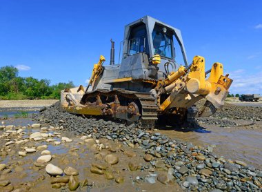 Buldozer, dağdaki küçük nehrin gelgitinde çalışır.