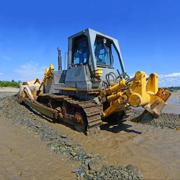 Buldozer, dağdaki küçük nehrin gelgitinde çalışır.