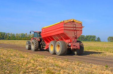Tahılları hasat etmek için karavanı olan bir traktör..