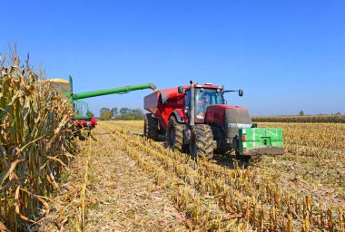 Kalush, Ukrayna 14 Ekim 2014: Batı Ukrayna 'nın Kaluş kenti yakınlarındaki tarlada tahıl hasadına giden tahılı taşımak için römorklu modern John Deere traktörü