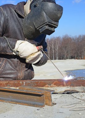 Metal bir yapıyı kaynak yapan bir adam.