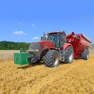 Kalush, Ukrayna 14 Ekim 2014: Batı Ukrayna 'nın Kaluş kenti yakınlarındaki tarlada tahıl hasadına giden tahılı taşımak için römorklu modern John Deere traktörü