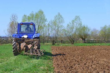 Traktördeki adam tarlayı sürüyor.