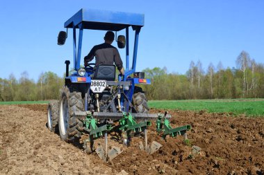 Traktördeki adam tarlayı sürüyor.