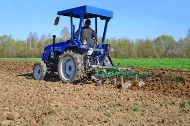 Traktördeki adam tarlayı sürüyor.