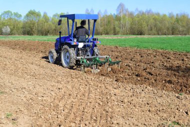 Traktördeki adam tarlayı sürüyor.
