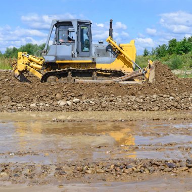 Buldozer, dağdaki küçük nehrin gelgitinde çalışır.