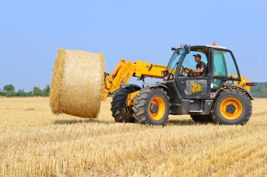 Kalush, Ukraine - August 13: Universal loader harvesting straw in the field near the town Kalush, Western Ukraine August 13, 2015