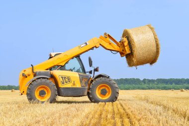 Kalush, Ukraine - August 13: Universal loader harvesting straw in the field near the town Kalush, Western Ukraine August 13, 2015