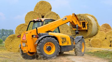 Kalush, Ukraine - August 13: Universal loader harvesting straw in the field near the town Kalush, Western Ukraine August 13, 2015
