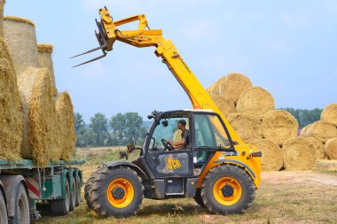 Kalush, Ukraine - August 13: Universal loader harvesting straw in the field near the town Kalush, Western Ukraine August 13, 2015