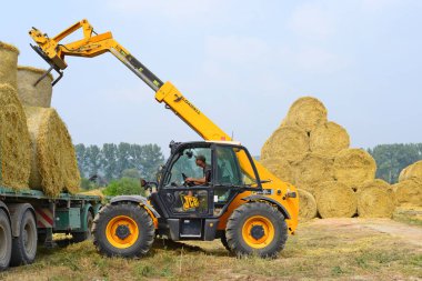 Kalush, Ukraine - August 13: Universal loader harvesting straw in the field near the town Kalush, Western Ukraine August 13, 2015