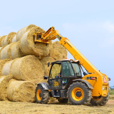 Kalush, Ukraine - August 13: Universal loader harvesting straw in the field near the town Kalush, Western Ukraine August 13, 2015